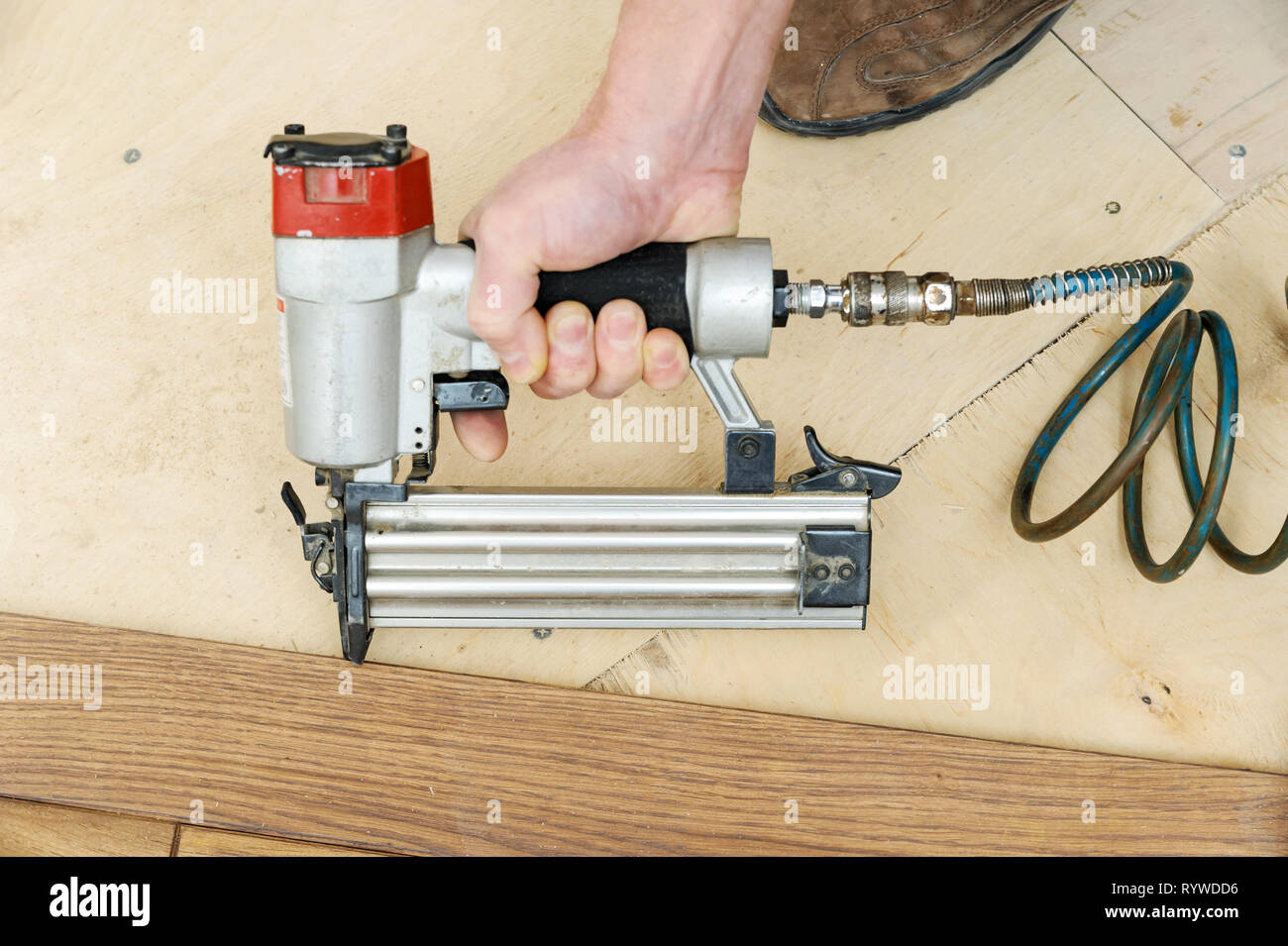 Installing A Wooden Floor A Worker Fixes The Board Using A
