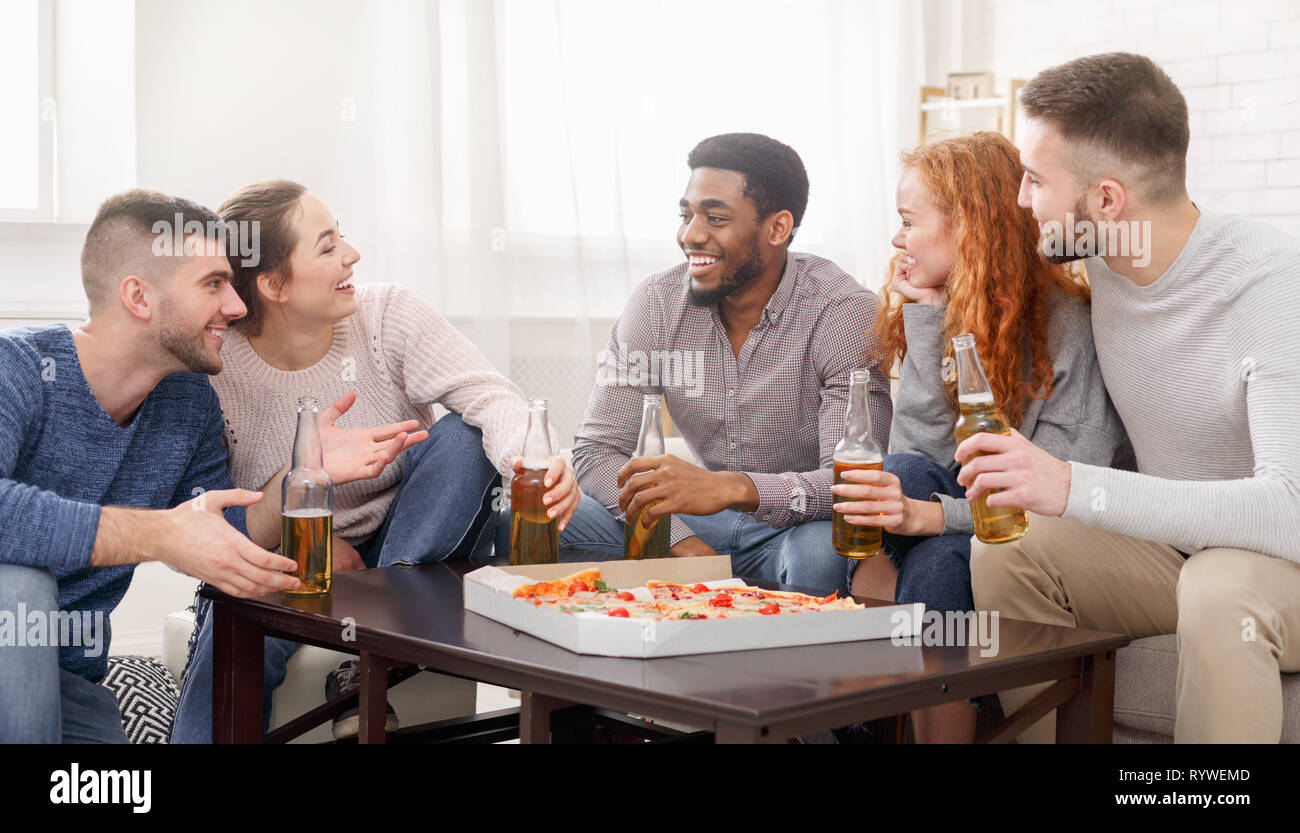 Time for snack. Happy friends eating pizza and drinking beer Stock Photo
