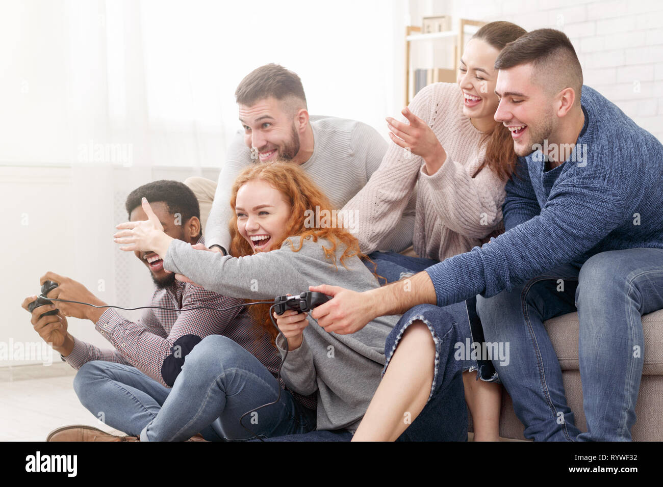 Excited friends playing video games together, having fun Stock Photo