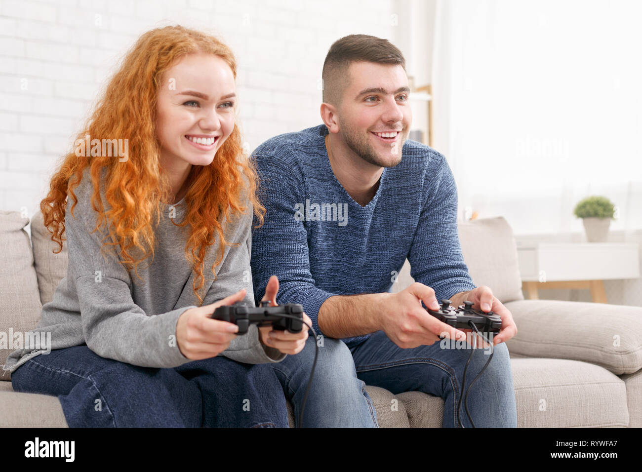 Cheerful boyfriend and girlfriend playing video games to win. Happy couple  using controller to play online game and winning gameplay on console.  People holding joystick to have fun Stock Photo - Alamy