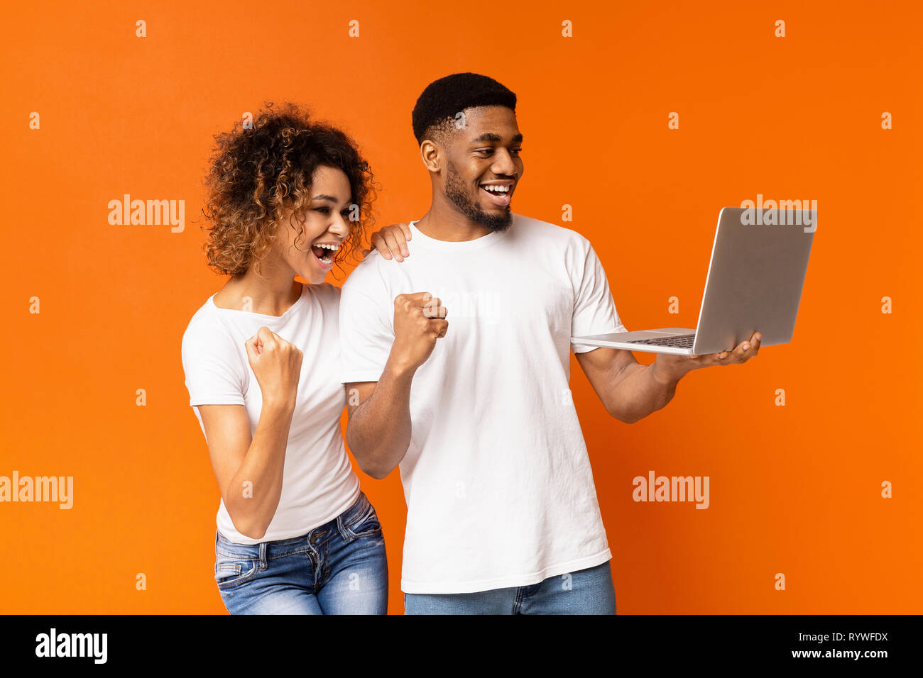 Excited black couple celebrating win with laptop Stock Photo - Alamy