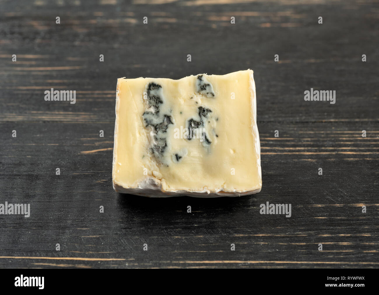 Slice of brie cheese with mold on a dark table Stock Photo