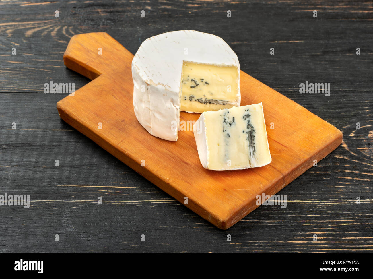 Brie cheese with slice on cutting board and wooden background Stock Photo