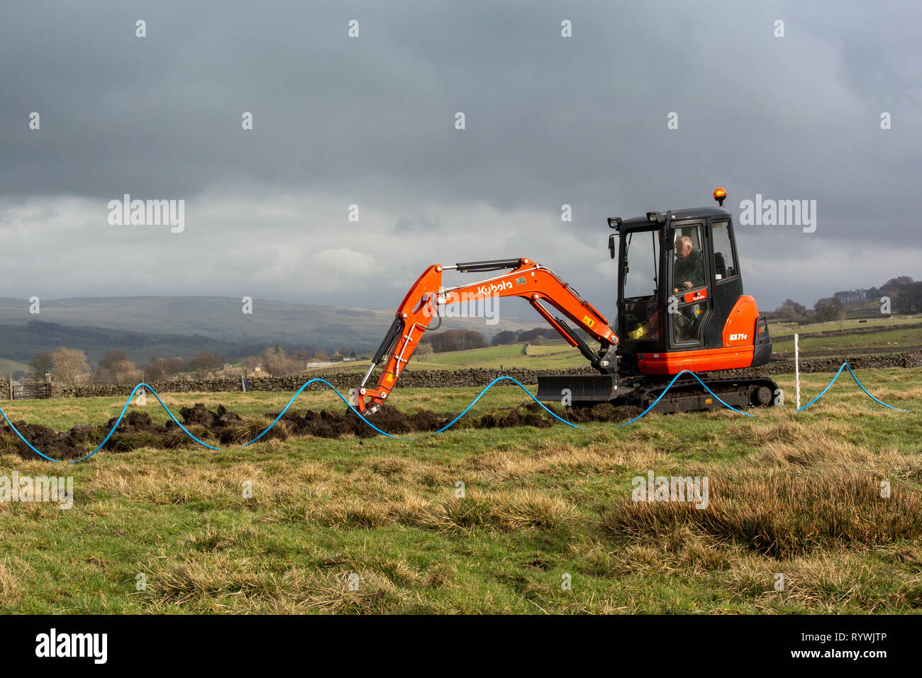 Digging a trench across a field to install a water supply to a field. North Yorkshire, UK. Stock Photo