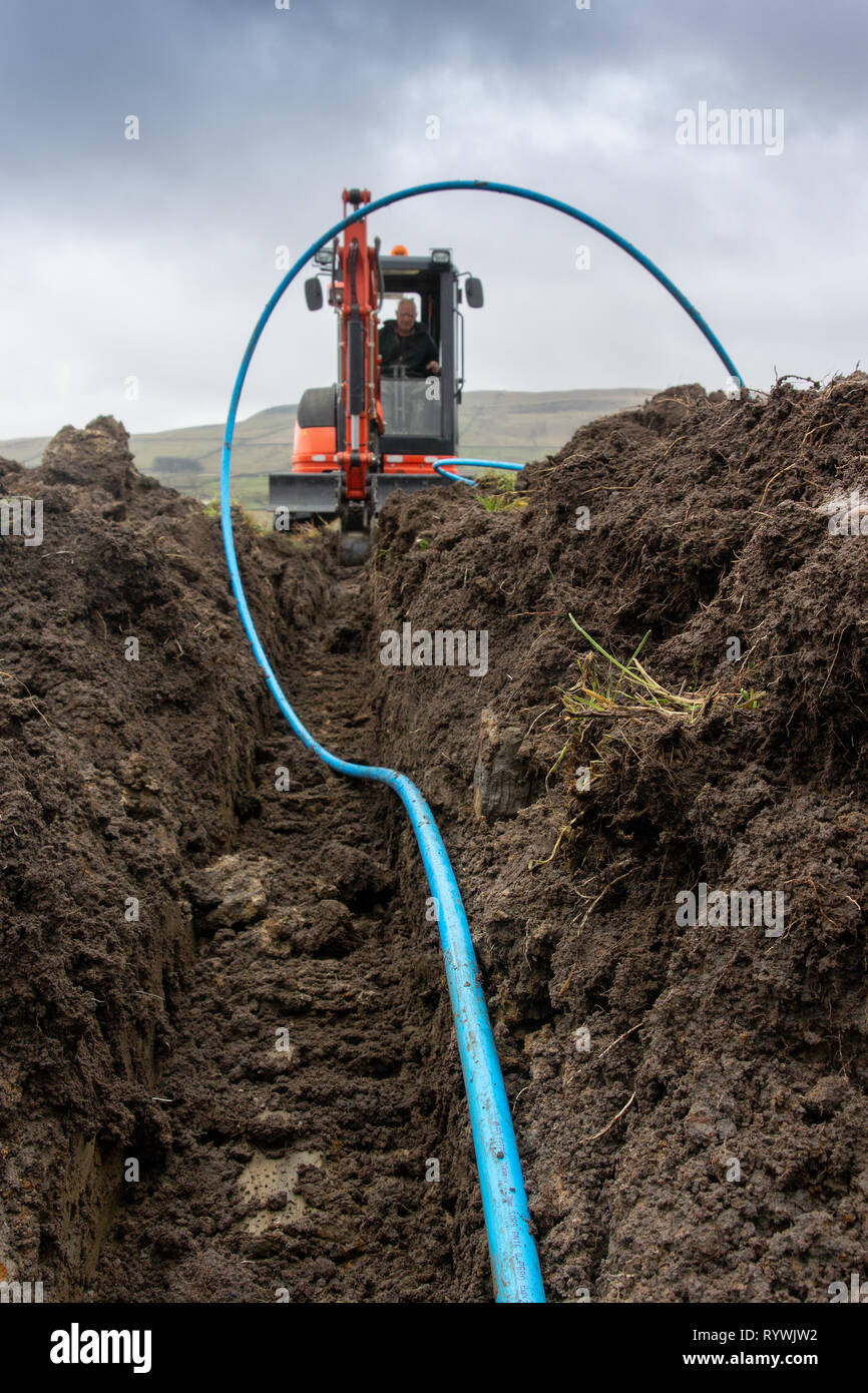 Digging a trench across a field to install a water supply to a field. North Yorkshire, UK. Stock Photo
