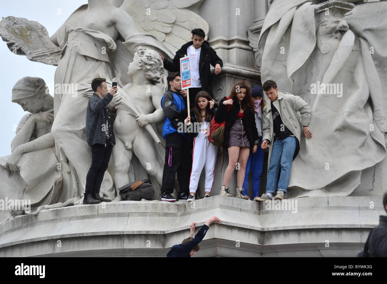 Students climbing the Queen Victoria Memorial outside Buckingham Palace in London during the global school strike for climate change. Stock Photo