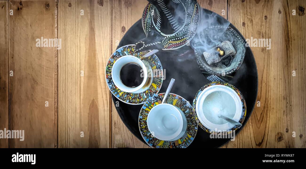 Ethiopian Buna Coffee ceremony, a Traditional Coffee Roasting and Drinking Ceremony with frankincense. Teapot and teacups viewed from above. Stock Photo