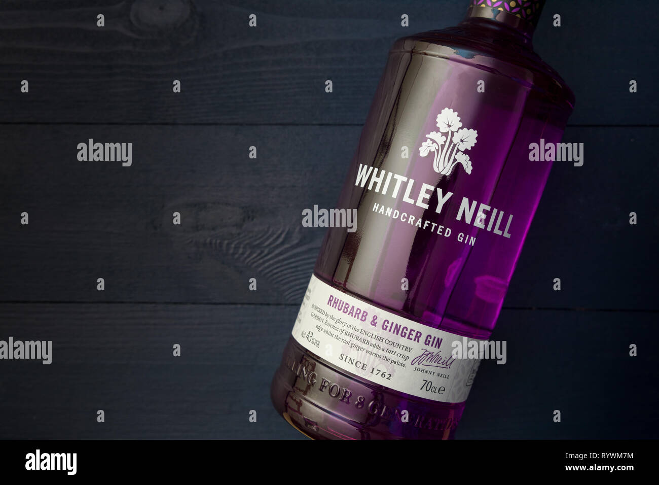 LONDON - MARCH 13, 2019: Whitley Neill Rhubarb Ginger Gin in purple glass bottle on dark wood background Stock Photo