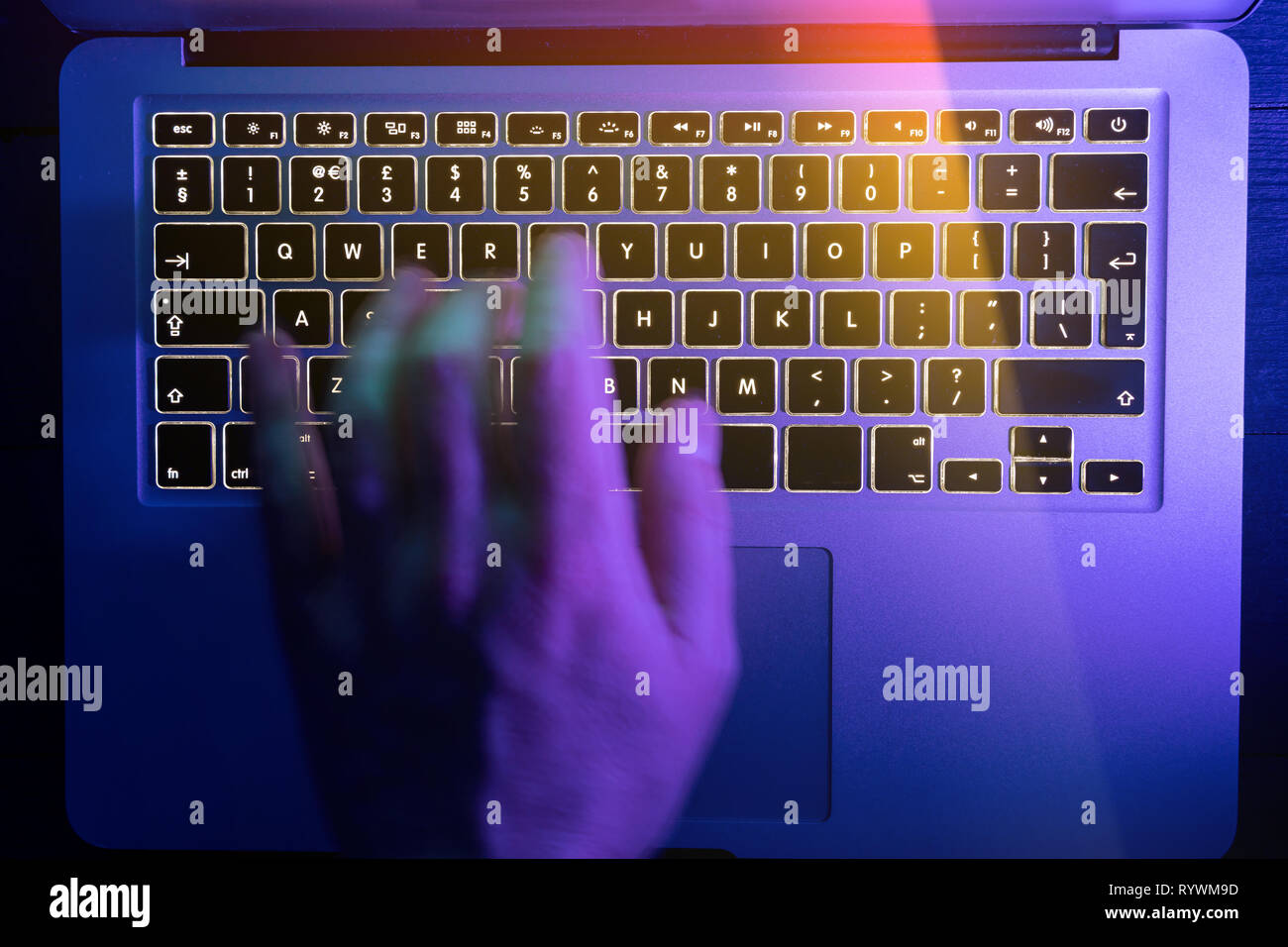 Man typing on laptop computer keyboard at night online cyber crime hacker concept Stock Photo