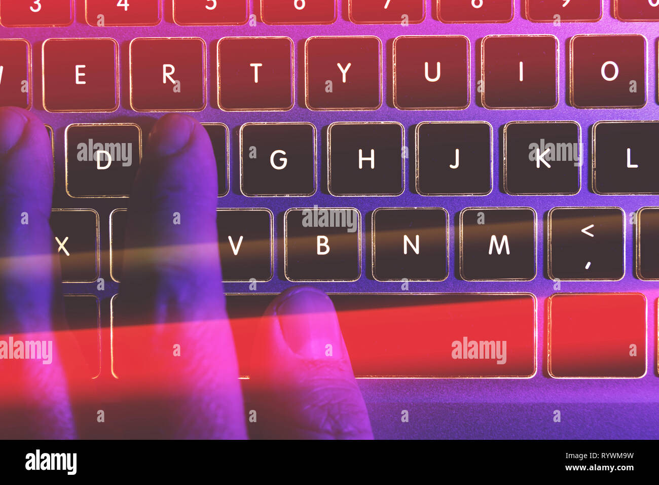 Man typing on laptop computer keyboard at night online cyber crime hacker concept Stock Photo