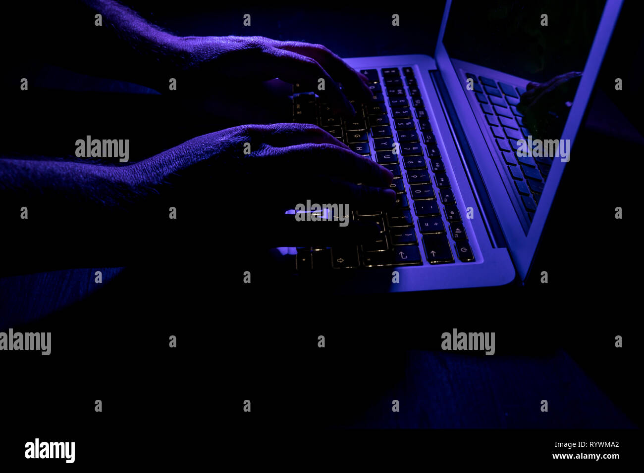 Man typing on laptop computer keyboard at night online cyber crime ...