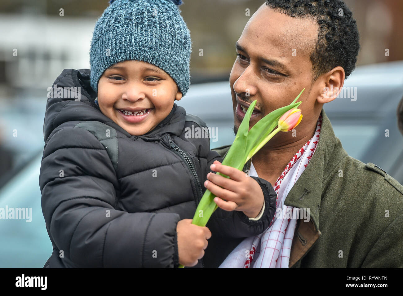 Jabiral Abdi, two, from Birmingham, with his dad Said Abdi, holds a yellow flower given to him by Christian James Lynch, from Riverside Church, who is handing out flowers to Muslims as they leave Birmingham Central Mosque after the attack on the Mosque in Christchurch, New Zealand. Stock Photo