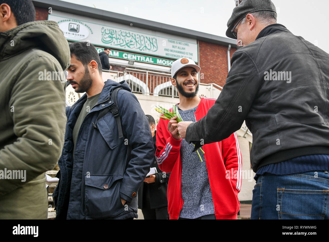 A man smiles as Christian James Lynch, from Riverside Church, hands out flowers to Muslims as they leave Birmingham Central Mosque as Friday prayers finish after the attack on the Mosque in Christchurch, New Zealand. Stock Photo