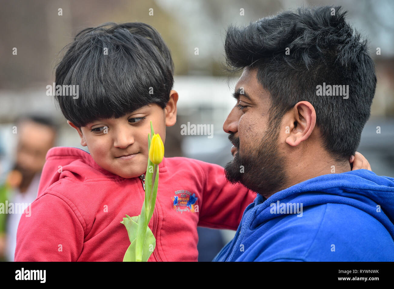 Aahil Ashraf, four, from Birmingham, with his dad Mohamed Ashraf, holds a yellow flower given to him by Christian James Lynch, from Riverside Church, who is handing out flowers to Muslims as they leave Birmingham Central Mosque after the attack on the Mosque in Christchurch, New Zealand. Stock Photo