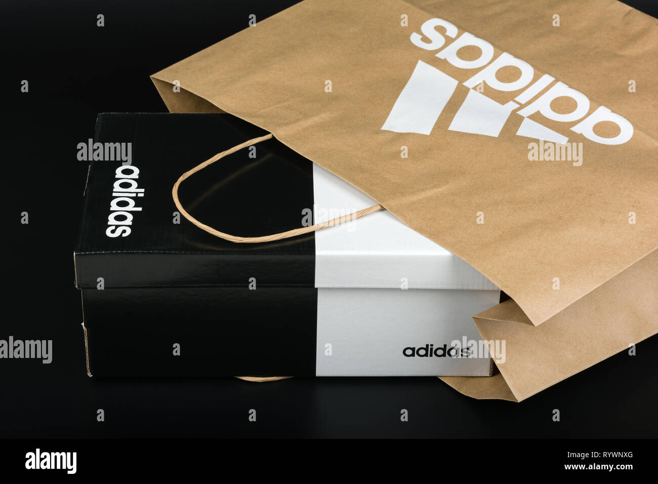 BURGAS, BULGARIA - MARCH 8, 2019: Paper bag with original Adidas logo and Adidas shoes box on black background. Stock Photo