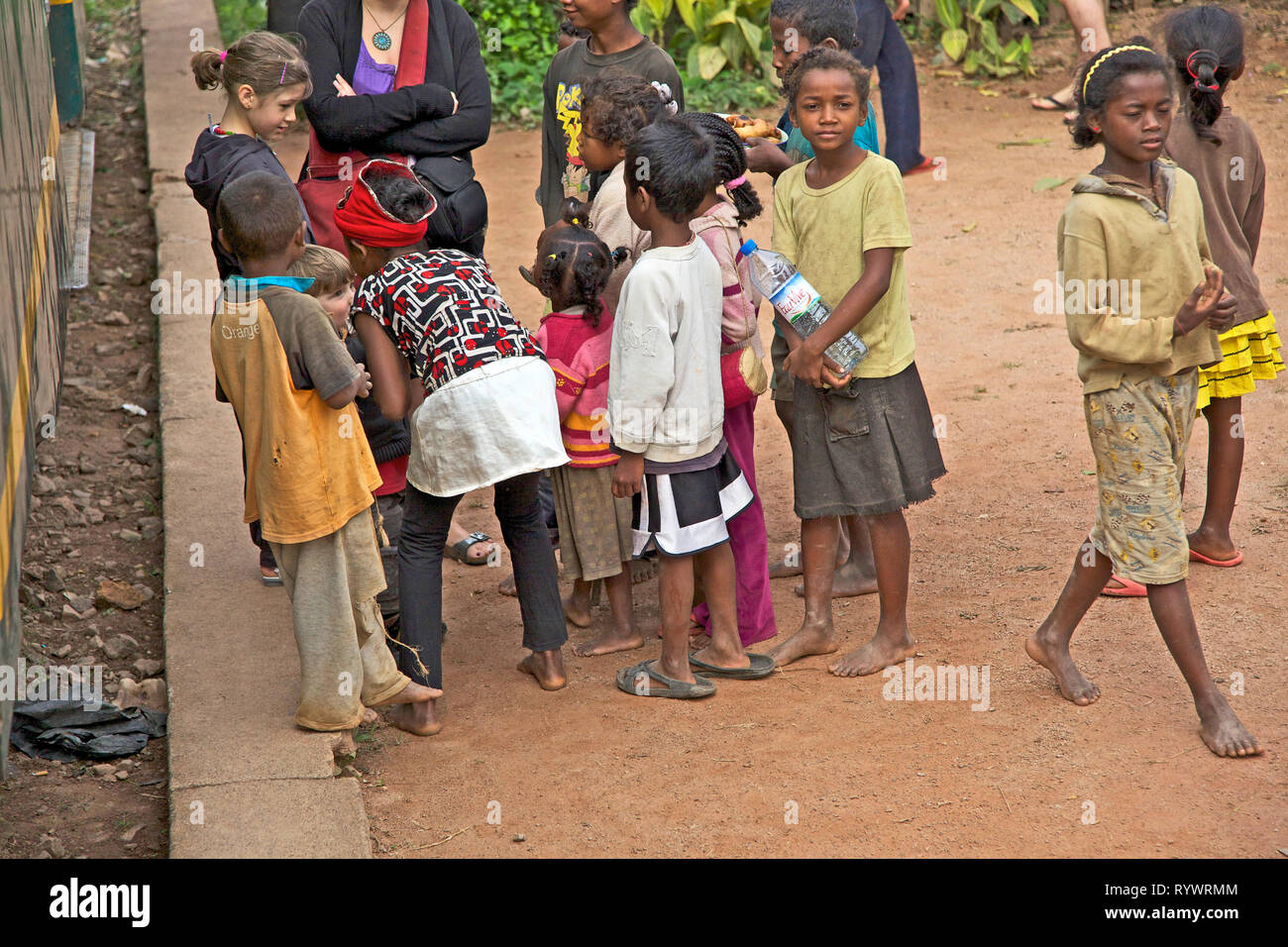 Local kids talking to young tourist children on the train station. The train Finarantsoa to Manakara. Madagascar. Stock Photo
