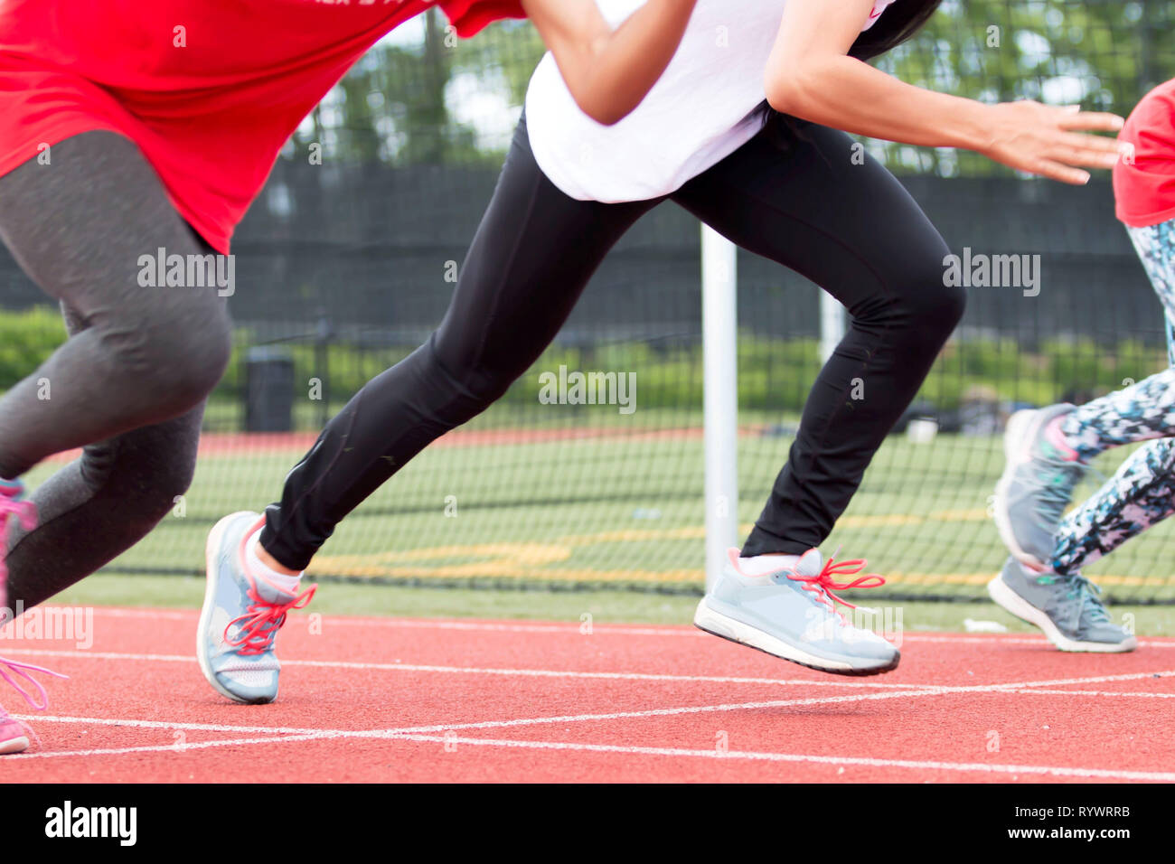 Three girls race each other sprinting at high school track and field