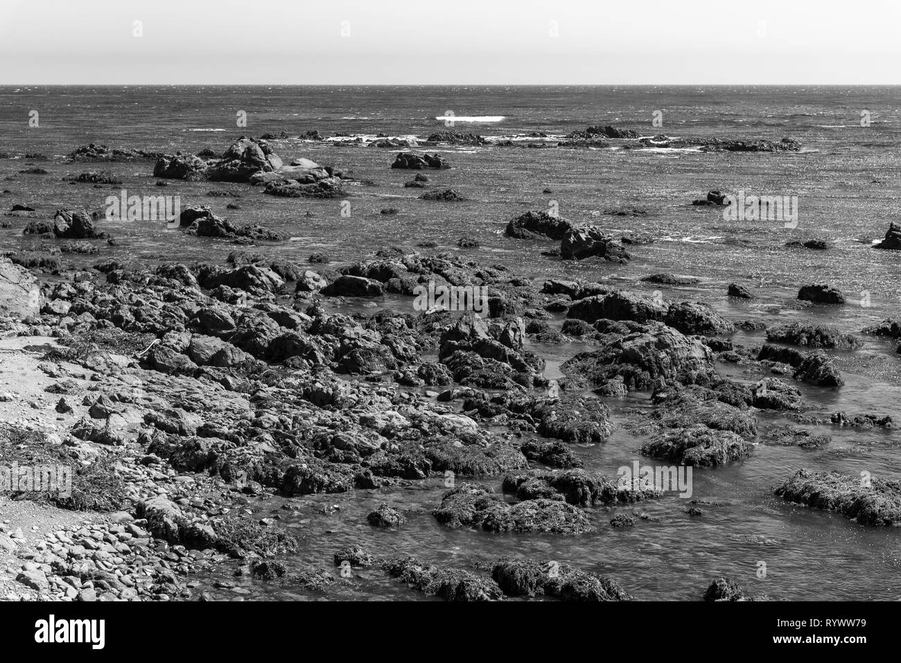 Black and white, rocky coast with small waves and horizon. Stock Photo