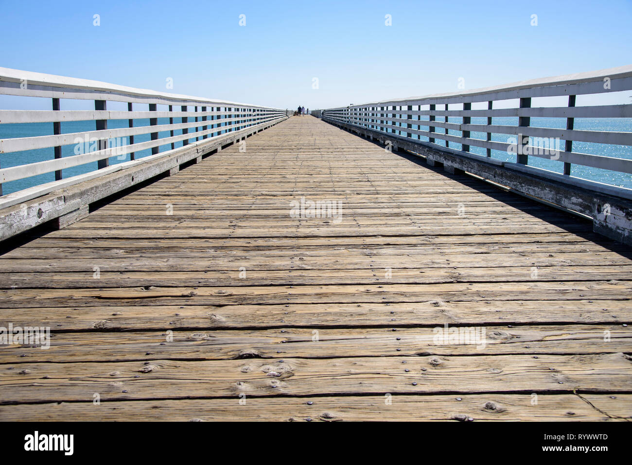 Pier with white guard rails under blue skies. Stock Photo
