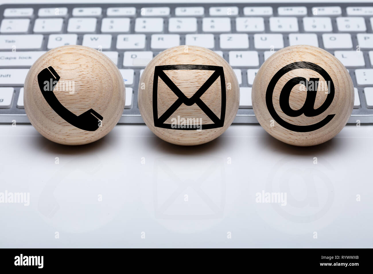Three Wooden Sphere Shape Ball With Contact Icon In Front Of White Keyboard Stock Photo