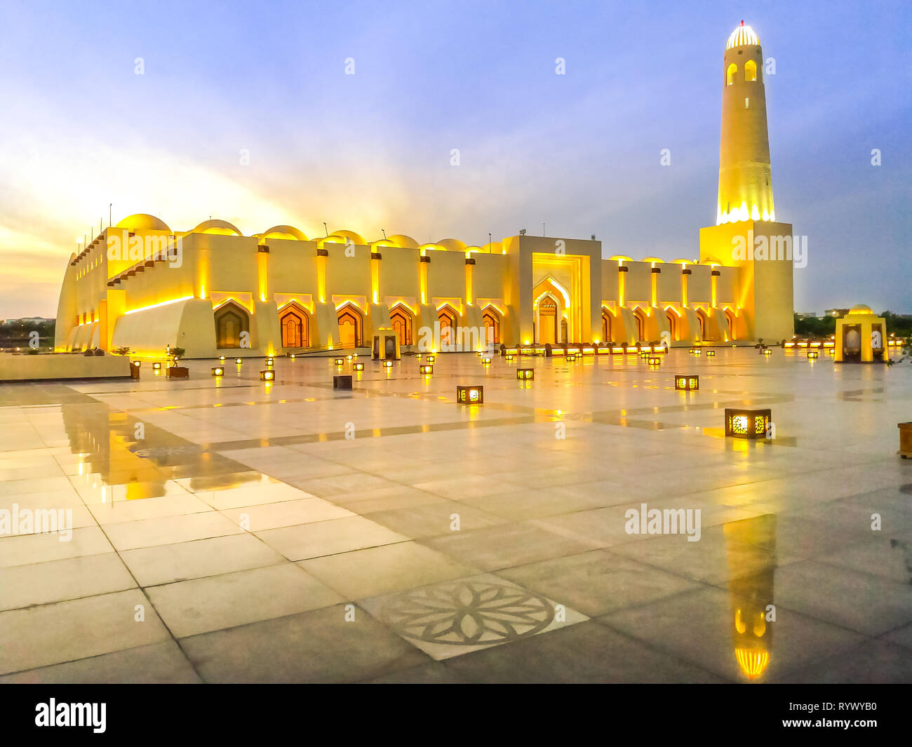 Scenic Doha Grand Mosque with minaret illuminated, mirrors on the outdoor marble pavement. Qatar State Mosque, Middle East, Arabian Peninsula in Stock Photo