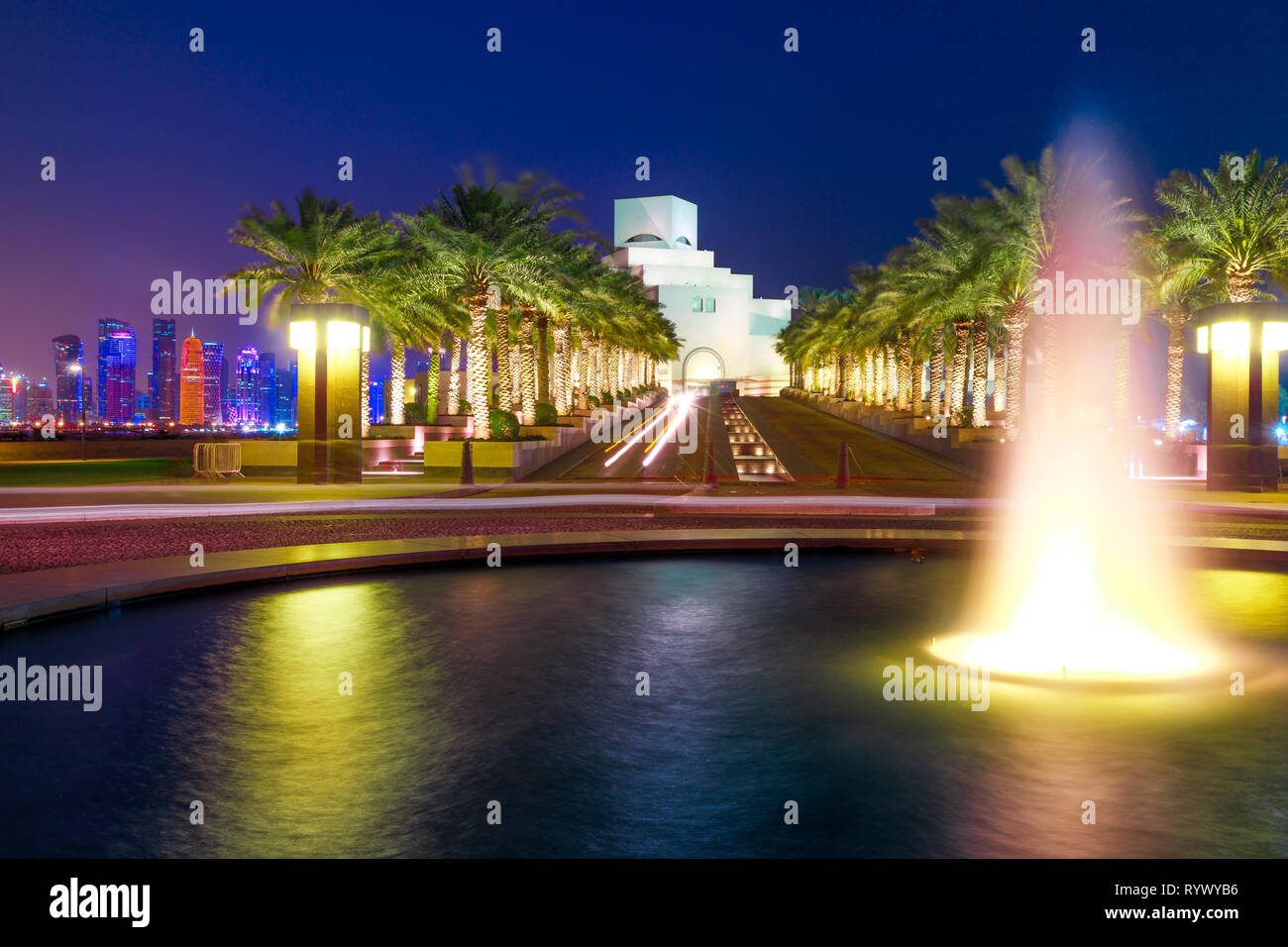 Fountain water reflecting near Corniche with skyscrapers of West Bay skyline illuminated on background. Doha, Qatari capital, in Middle East, Arabian Stock Photo