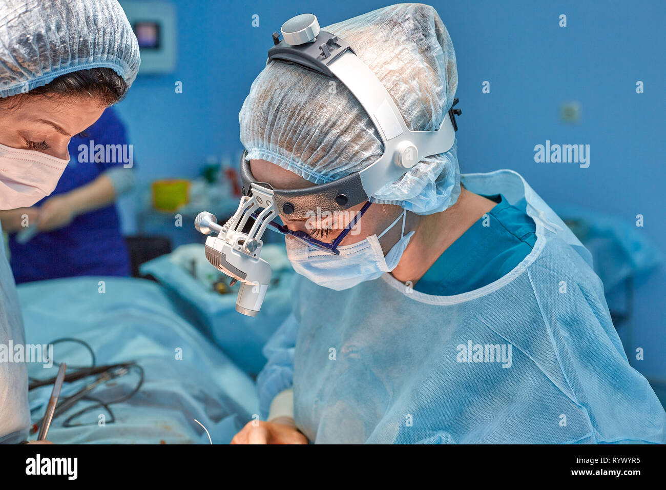 Professional smart intelligent surgeons standing near the patient and performing an operation while saving his life Stock Photo
