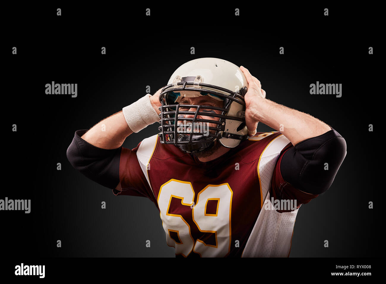 American football player in a helmet holding his head in pain against a
