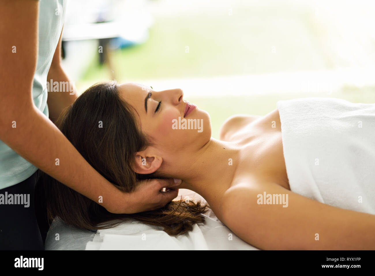 Young smiling woman receiving a head massage in a spa center. Stock Photo