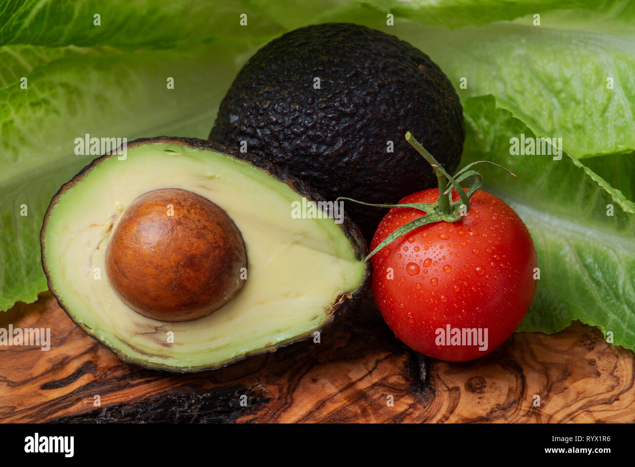 Fresh Organic Avocado Cut In Half And Organic Red Tomatoes On The