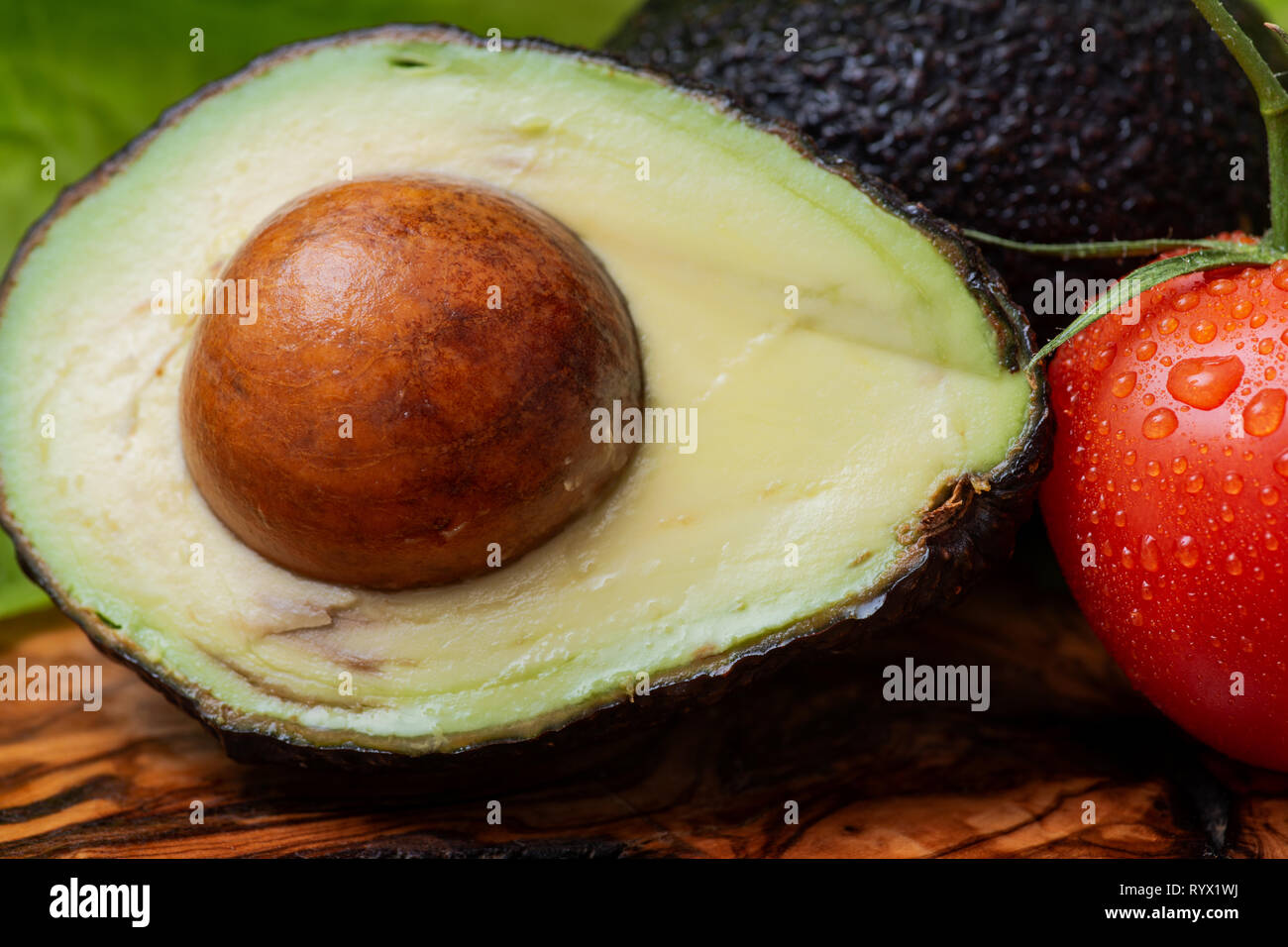 Fresh Organic Avocado Cut In Half And Organic Red Tomatoes On The