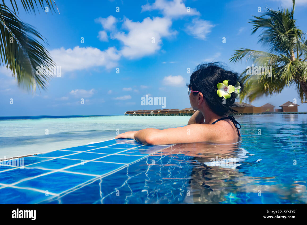 Girl looking at the ocean while sitting by the pool Stock Photo - Alamy