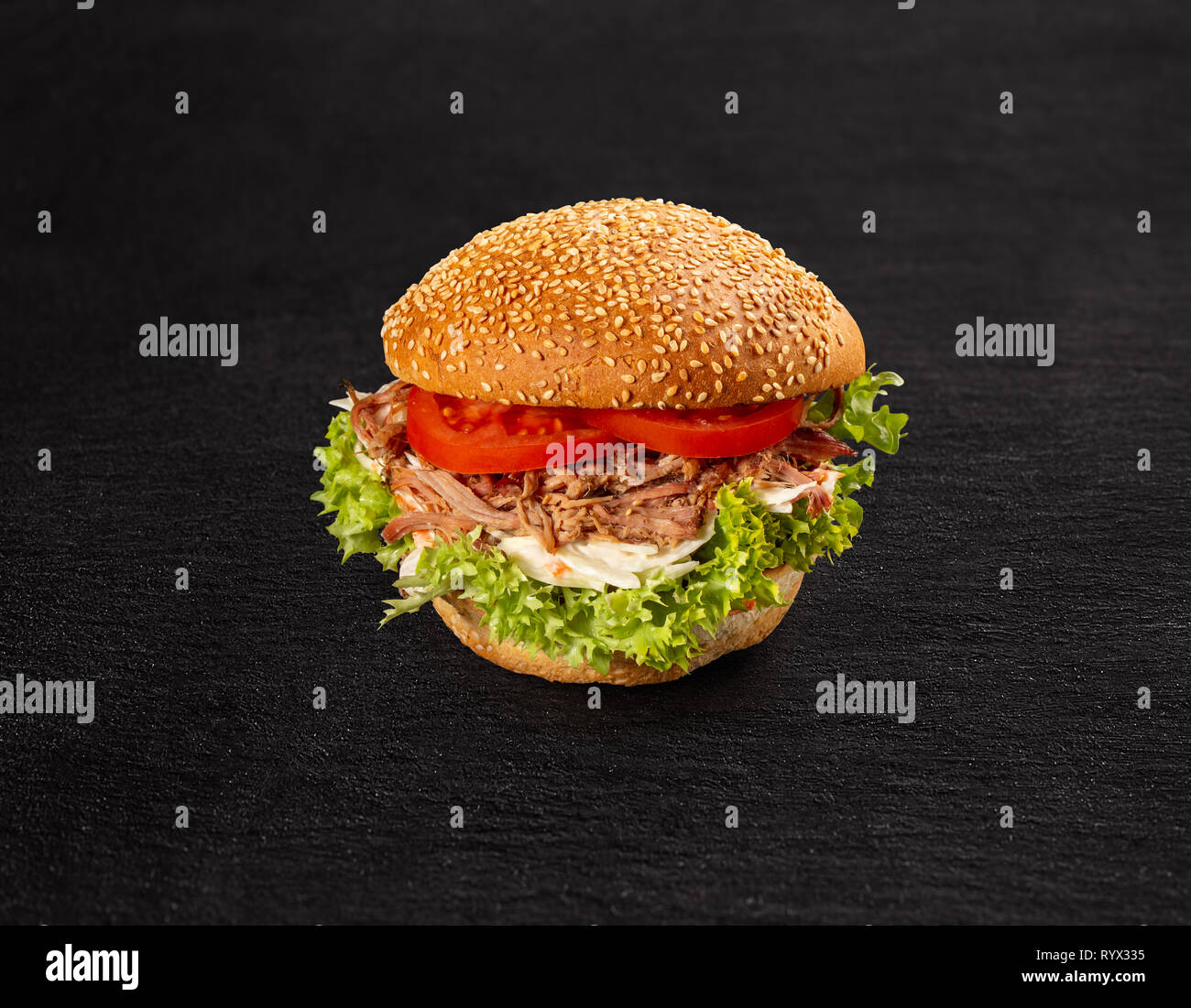 Pulled pork burger with fresh salad and tomato on dark background Stock Photo