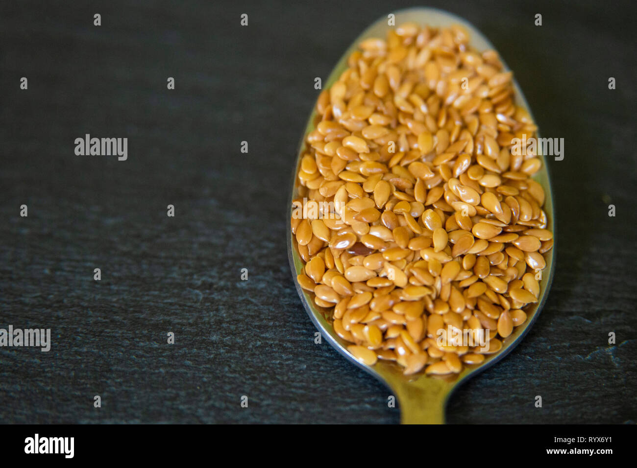 close up of flax seeds on a spoon on a dark slate background Stock Photo