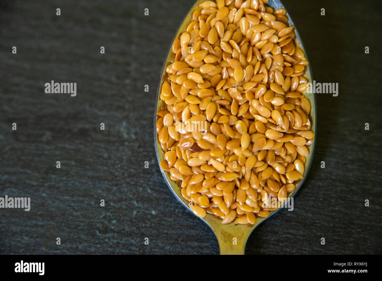 close up of flax seeds on a spoon on a dark slate background. Health fod Stock Photo