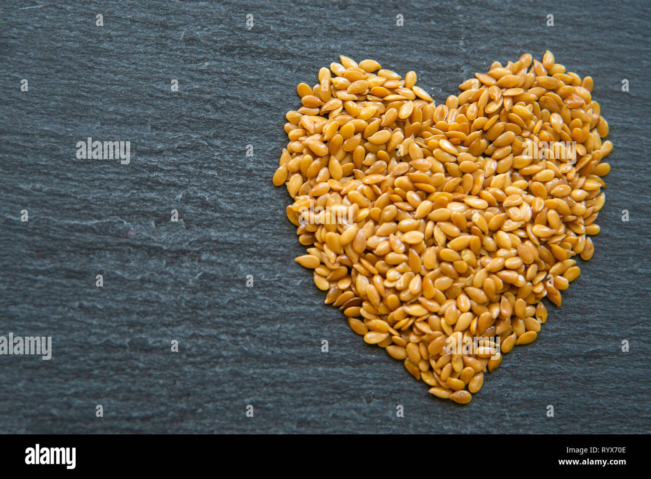 close up of flax seeds in a heart shape on a dark slate background Stock Photo