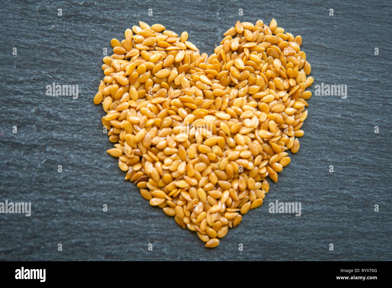 close up of flax seeds in a heart shape on a dark slate background Stock Photo