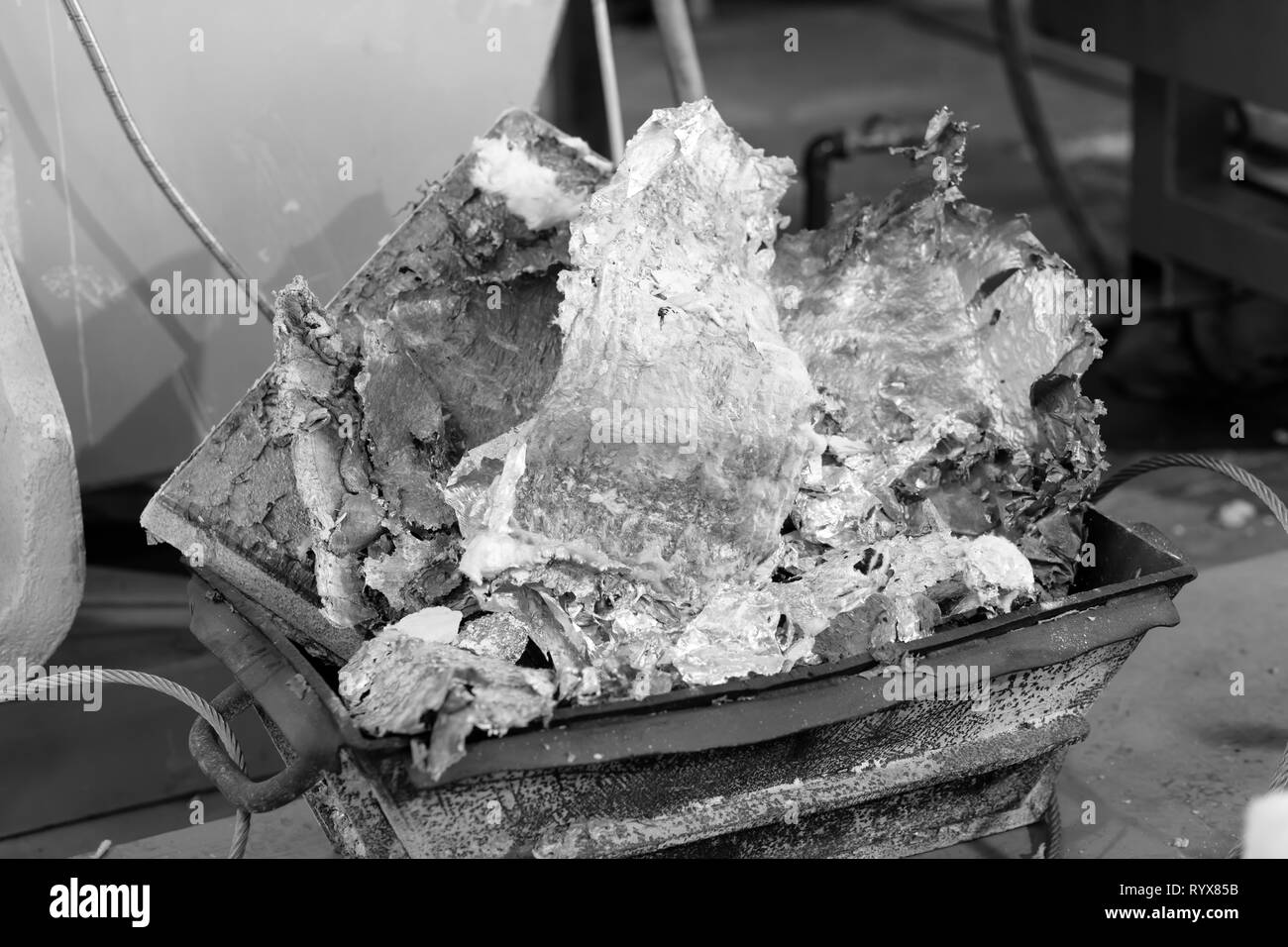 aluminum melted in a container recovered during foundry clean task. Industrial black and white photo Stock Photo