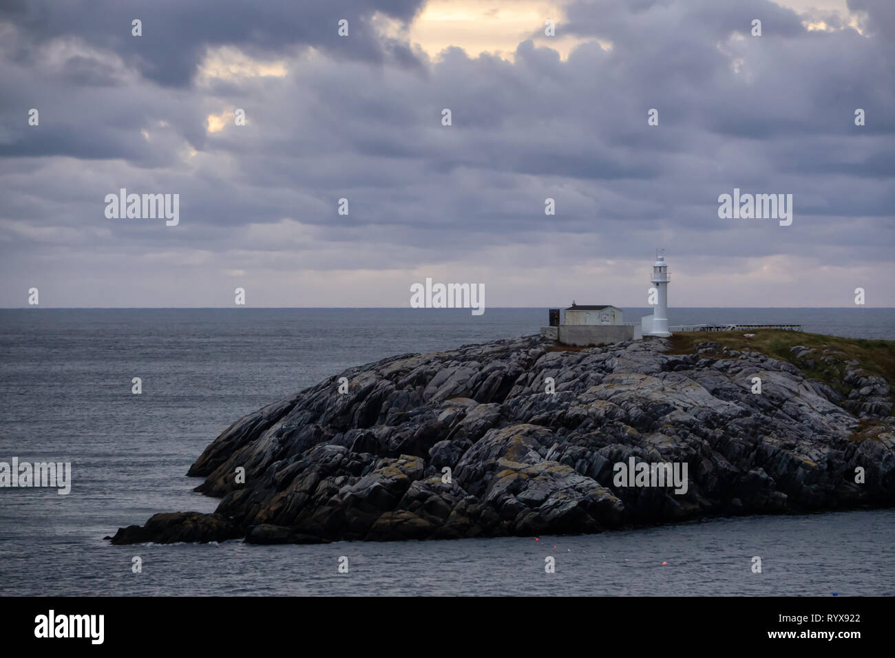 Lighthouse on the rocky Atlantic Ocean Coast during a cloudy sunset
