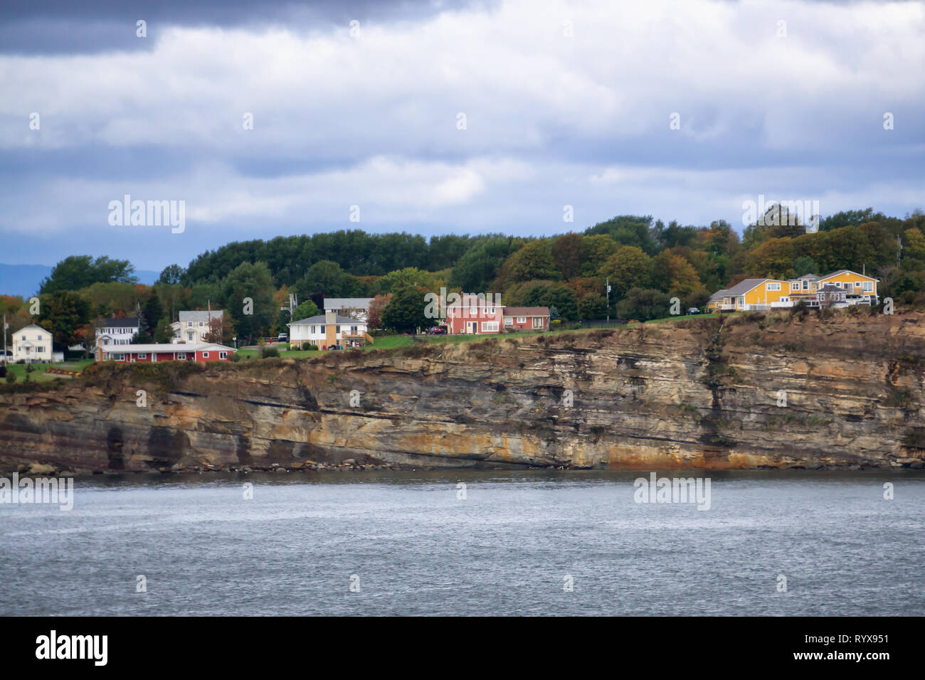 Residential homes on a rocky coast during a cloudy day. Taken in North Sydney, Nova Scotia, Canada. Stock Photo