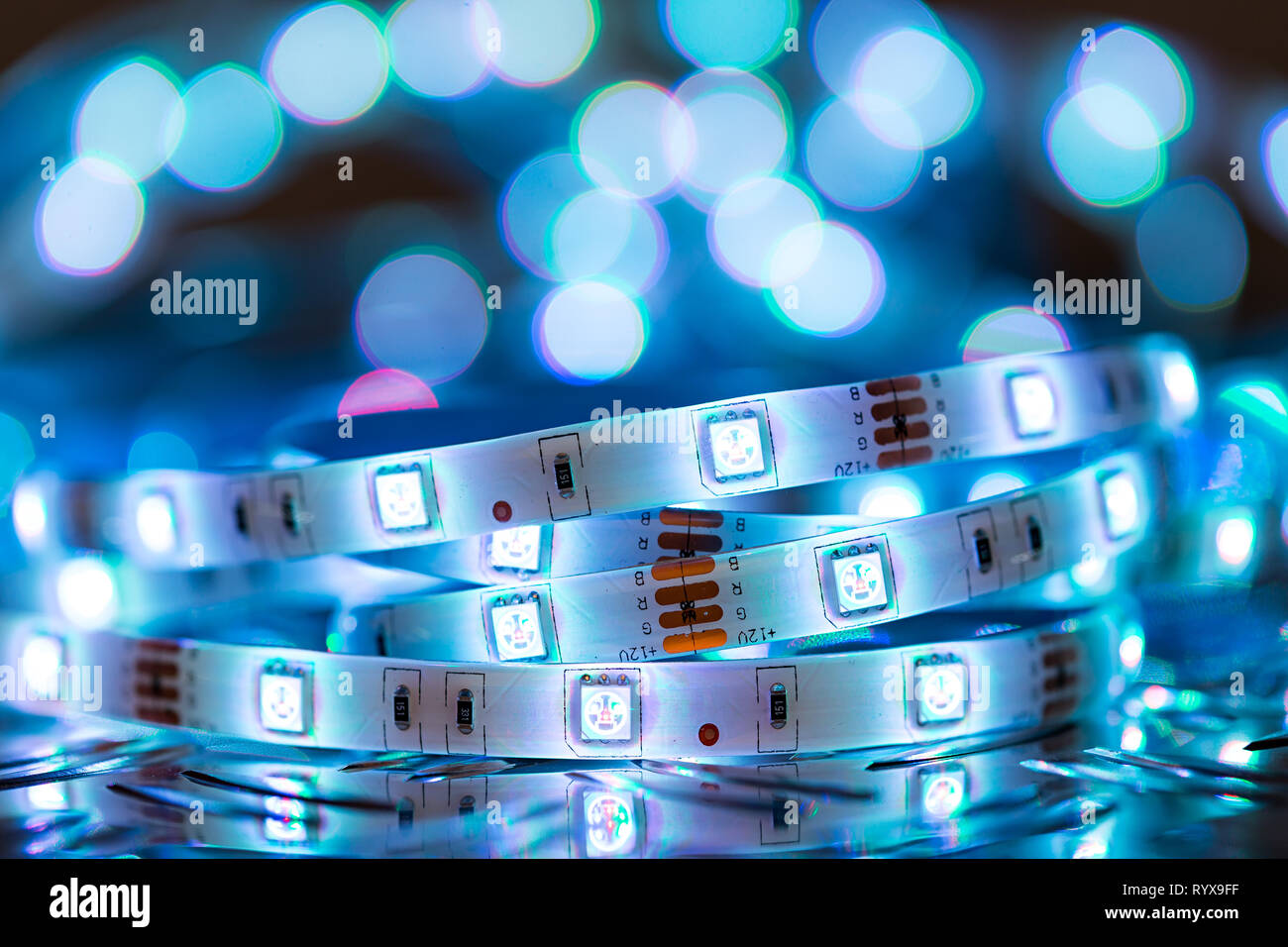 Bright RGB LED stripn light in front of colorful bokeh metal diamond plate electronics energy saving decoration technology background Stock Photo