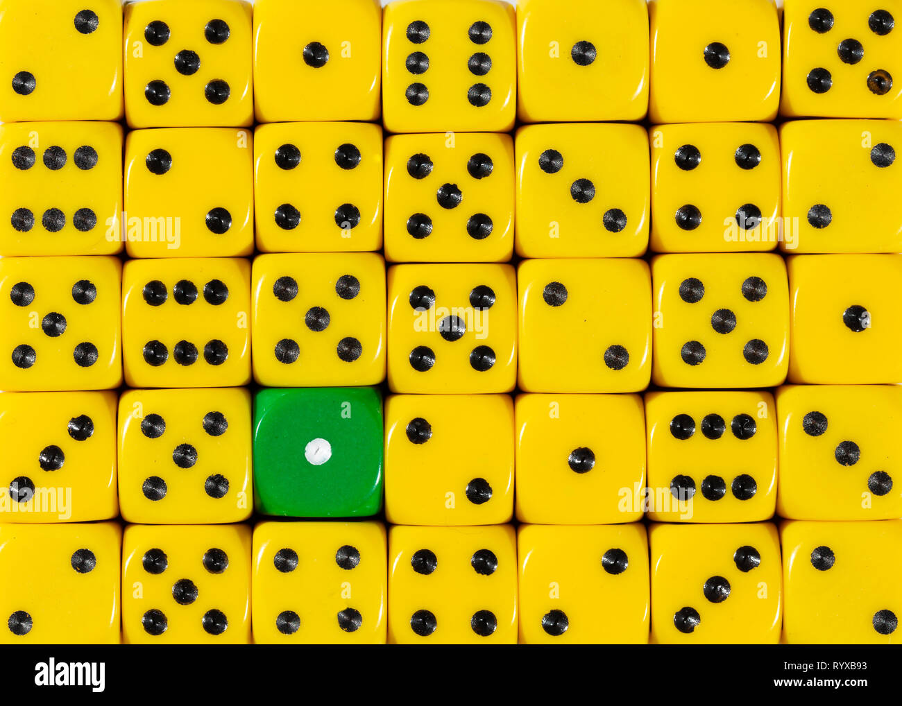 Background of random ordered yellow dices with one green cube Stock Photo