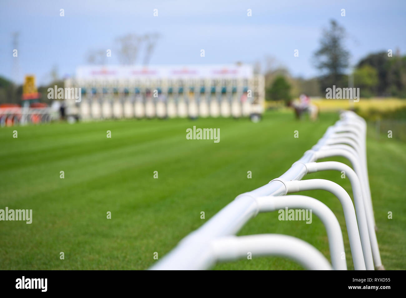 Racecourse in the early afternoon looking at the safety barriers with starting gates in the background Stock Photo