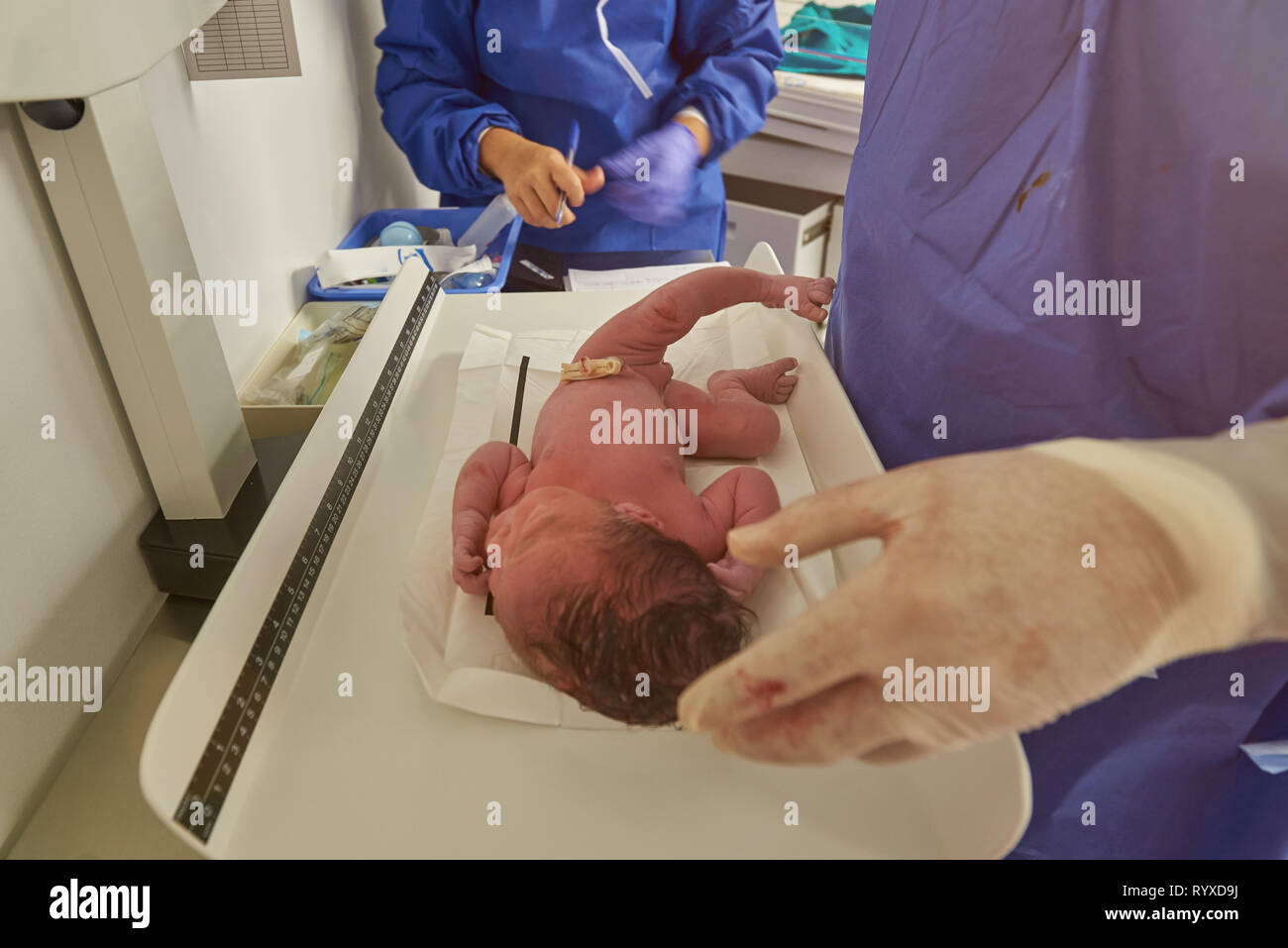 Measuring weight of newborn baby in hospital background Stock Photo