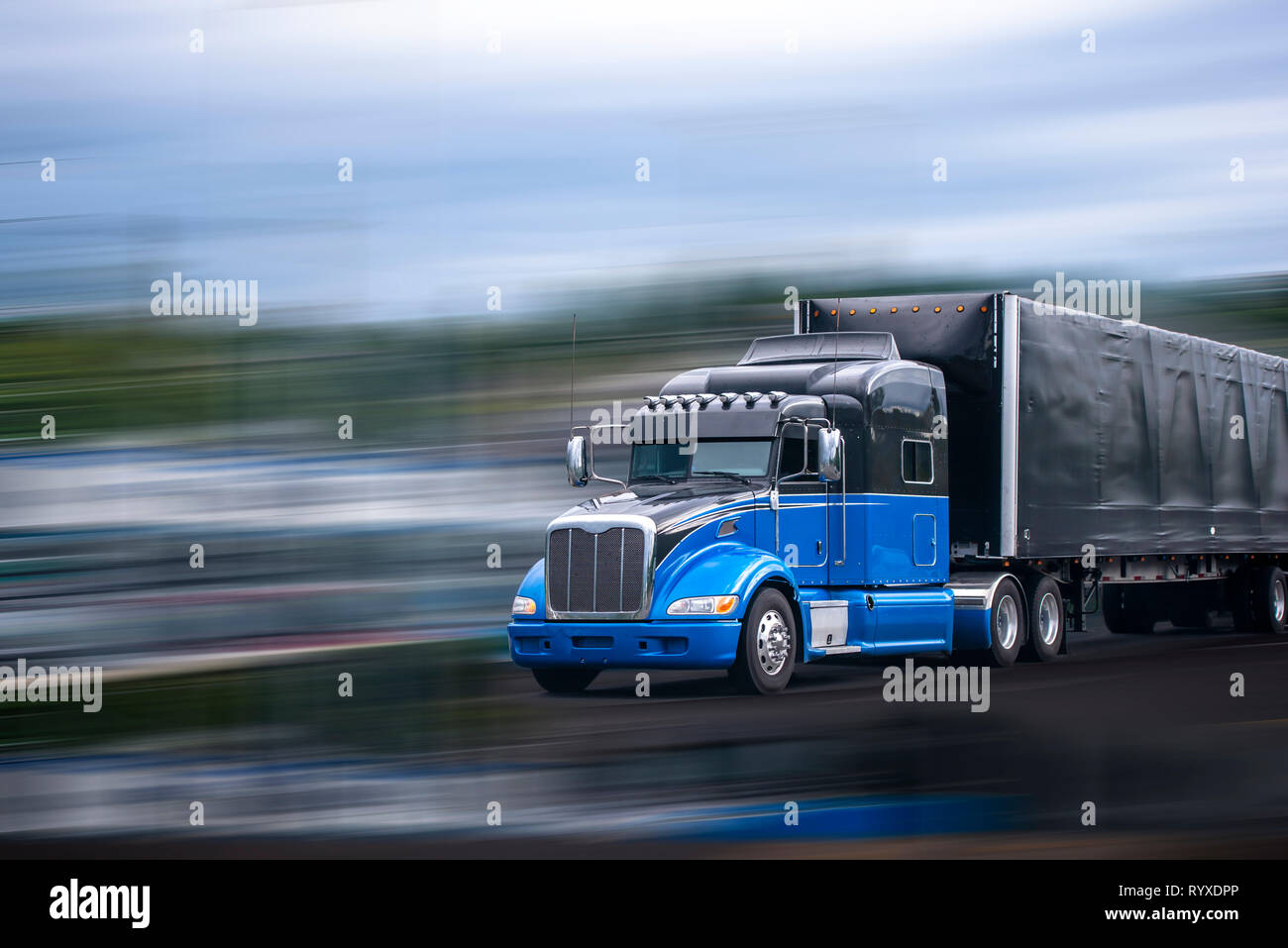 Stylish black and blue big rig long haul semi truck with aerodynamic