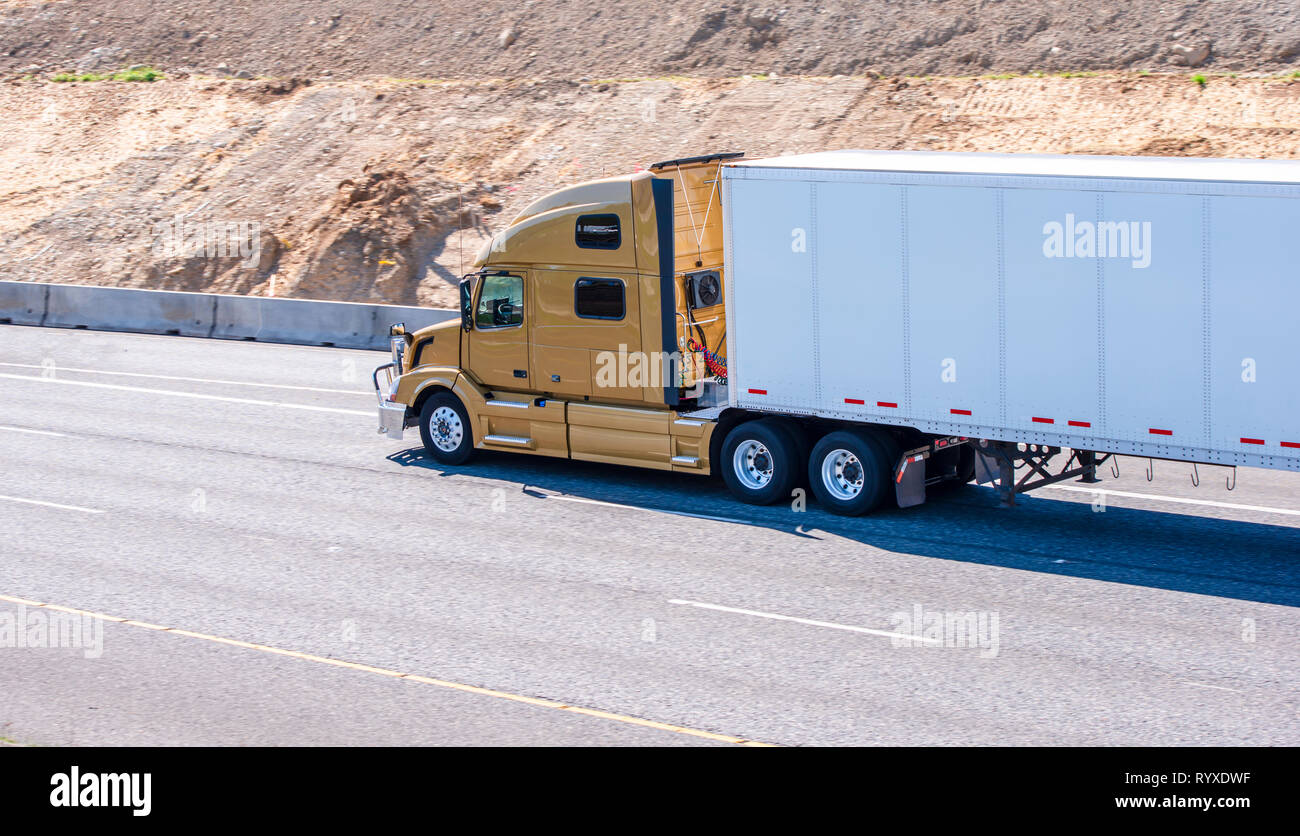 Gold powerful big rig professional comfortable semi truck transporting