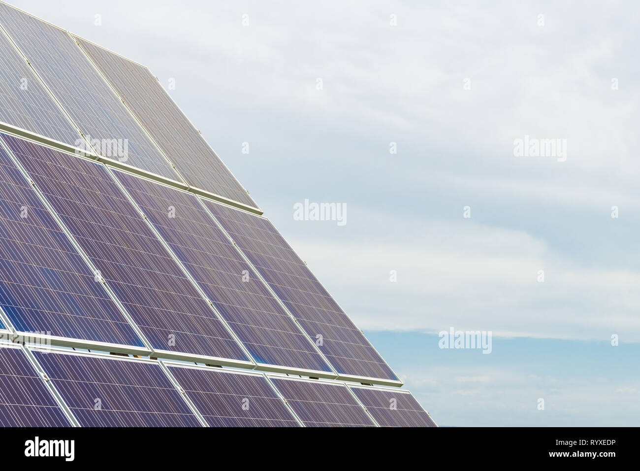 Solar cell photovoltaic panels at energy production plant with blue cloudy sky in the background. Solar renewable energy concept Stock Photo