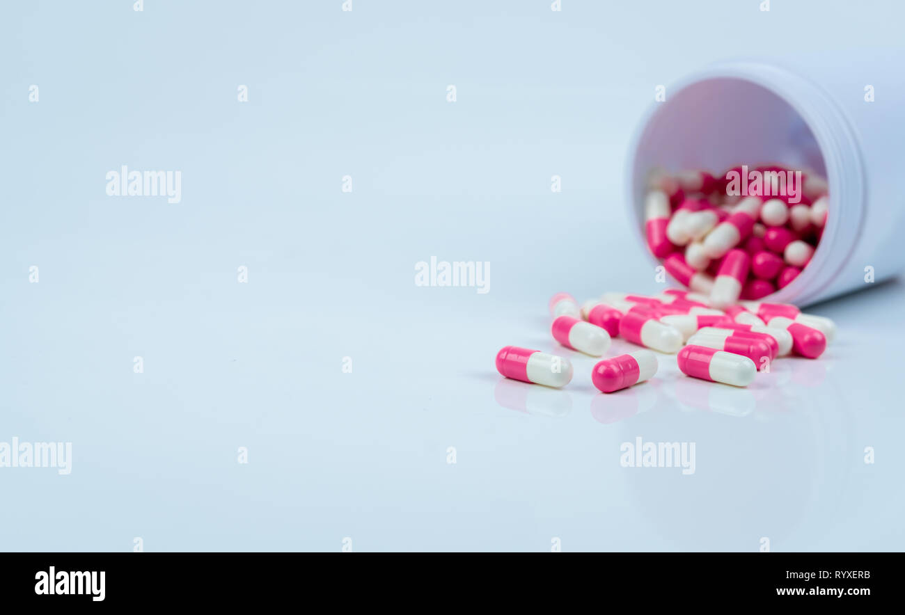 Pink-white capsule pills spread out of drug bottle. Antipsychotic drug. Capsule medicine for treatment depression. Anti-anxiety drug. Global healthcar Stock Photo