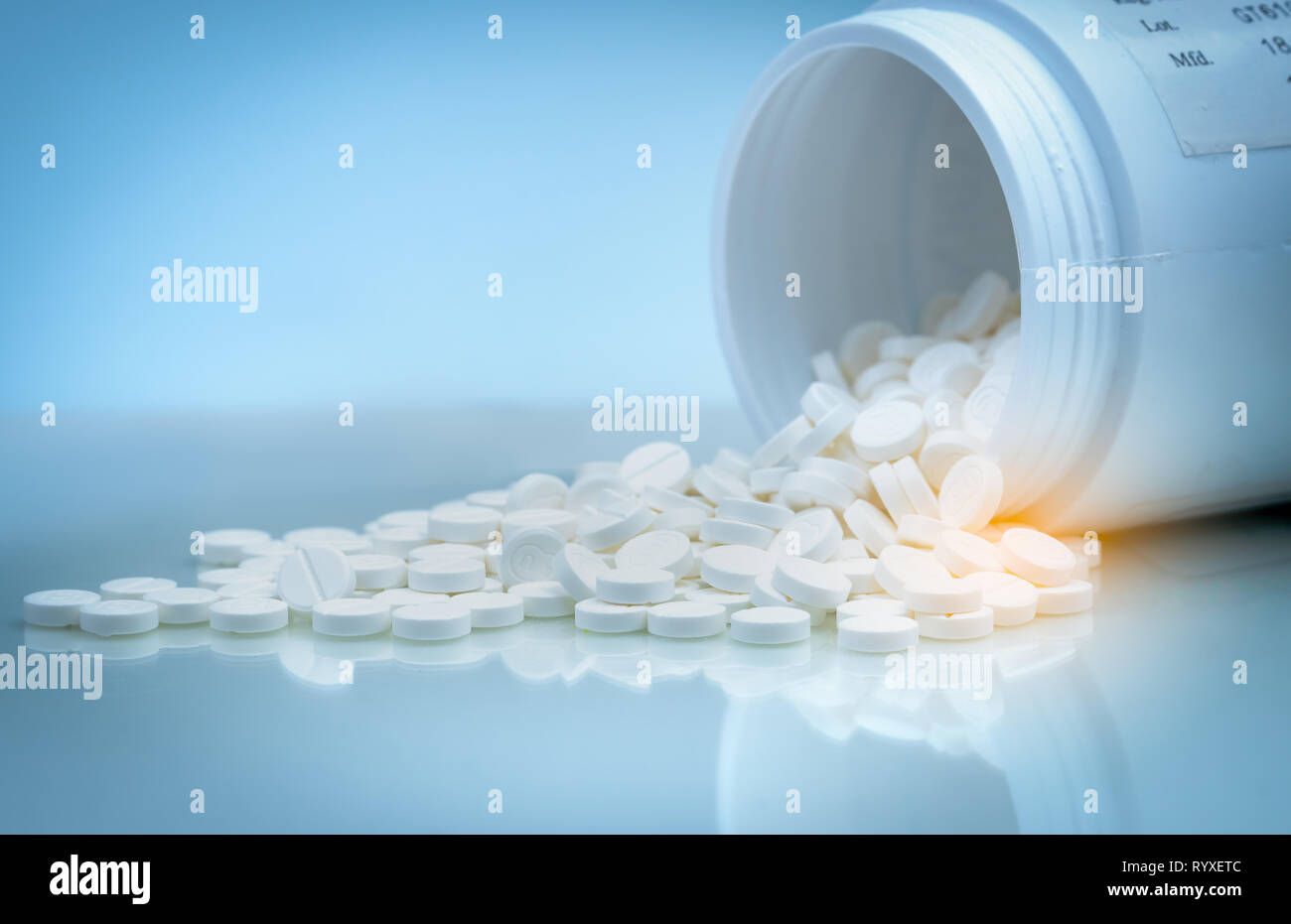 White tablets pill spilled out from white plastic bottle container. Pharmaceutical industry. Pharmacy product. Global healthcare. Drug use in hospital Stock Photo