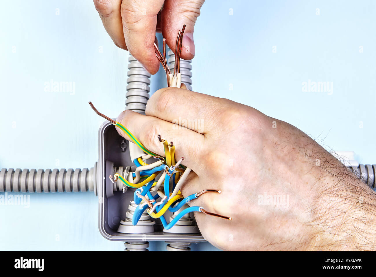 Electrician is twisting exposed wire ends of household power grid for good connection by hands. Stock Photo